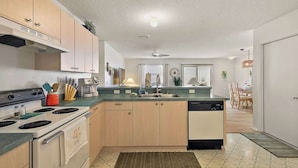 A modern kitchen with light wood cabinets, a central island, a dishwasher, and a stove.