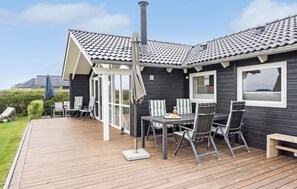 A deck with a table and chairs, a bench, and a covered seating area with a view of the landscape.