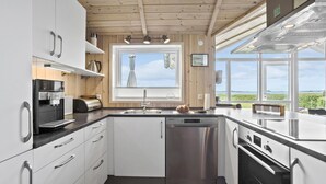 A modern kitchen with white cabinets, stainless steel appliances, and a view of the outdoors through large windows. - 3 bedroom awesome home in Faaborg (Faaborg)