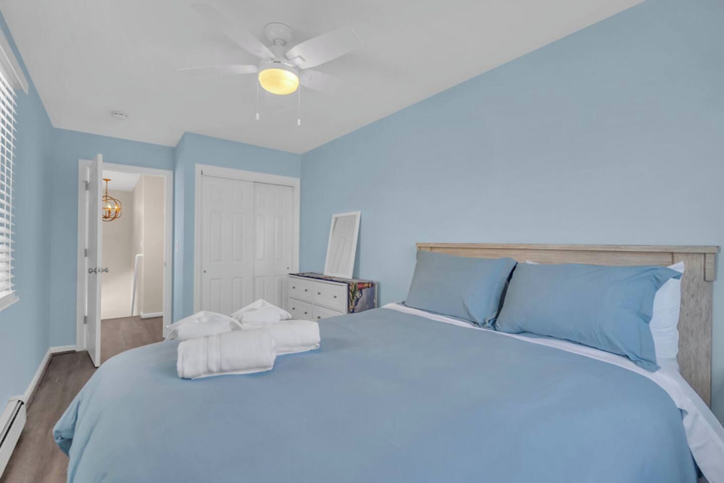 Un dormitorio con cama, ventilador de techo, cómoda y una puerta.