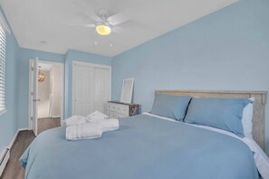 A bedroom with a bed, a ceiling fan, a dresser, and a door. - High Speed Wifi | Washer/Dryer | Linens+ Towels (Seaside Heights)