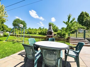 A patio with a round table and chairs, a swing set, and a barbecue grill. - Bastaja Rastoke by Interhome (Slunj)