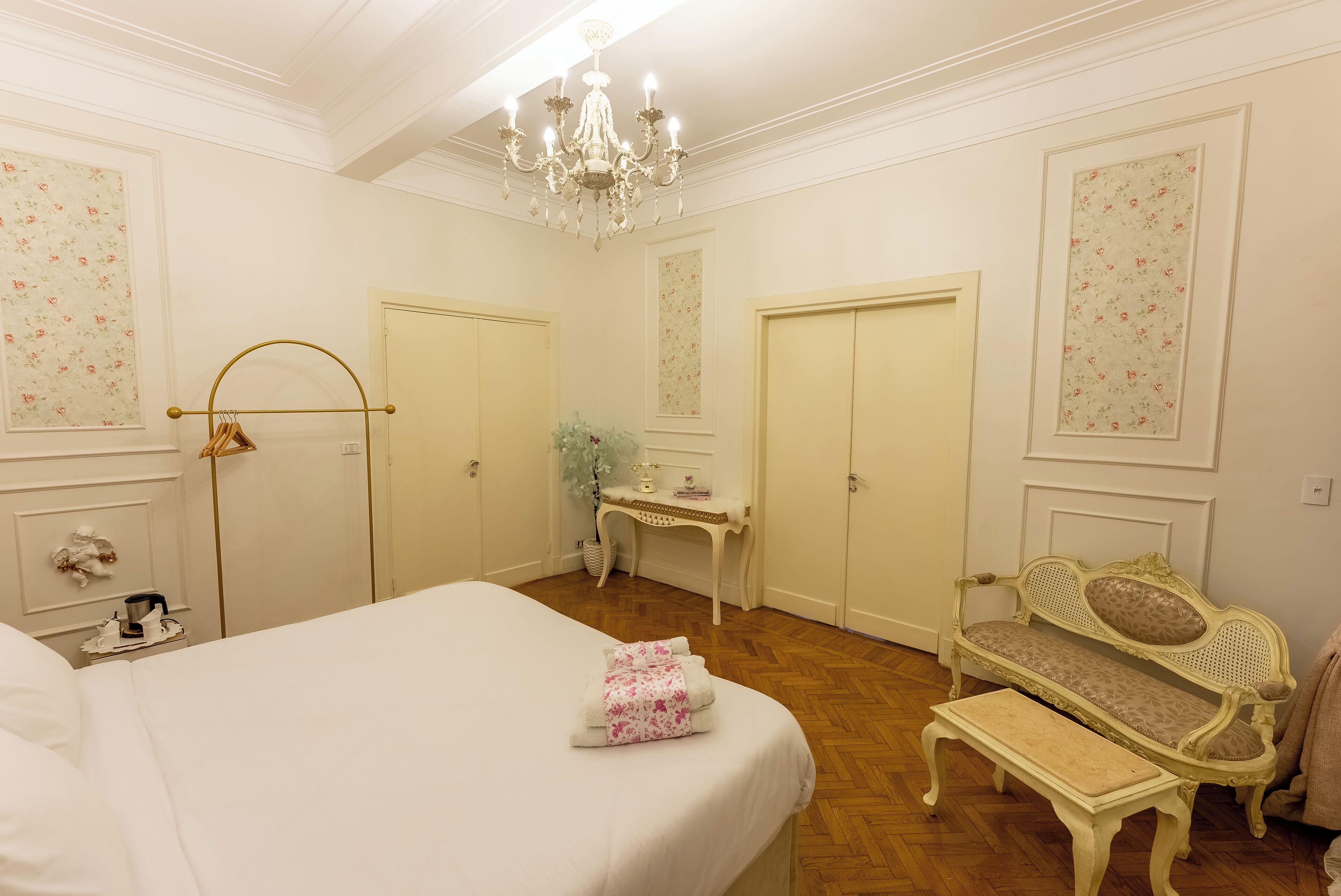 Una camera d'albergo con un letto grande, una panca, una scrivania e una sedia.
