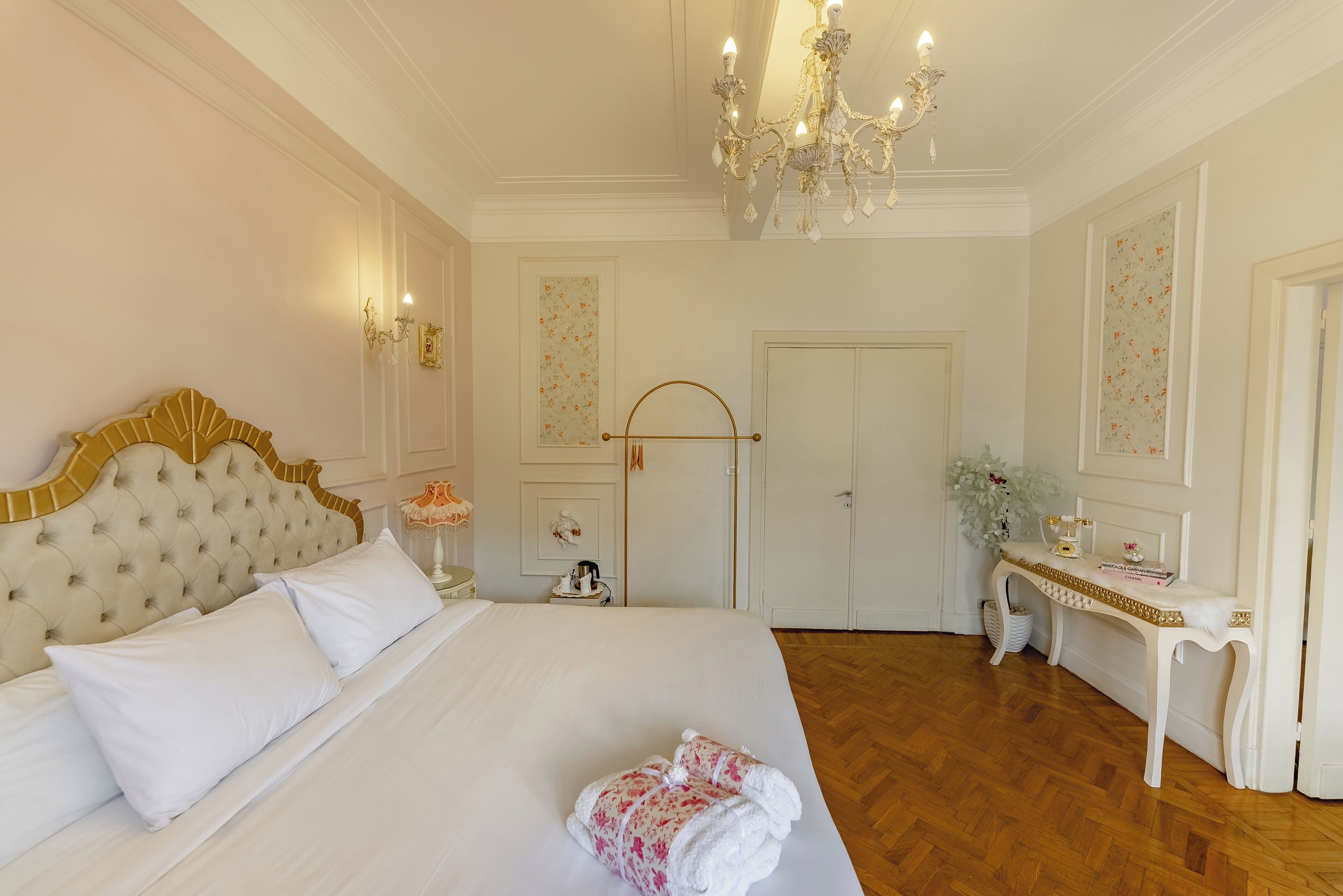 A spacious bedroom with a large bed, a chandelier, and a vanity with a mirror.