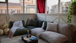 A cozy living room with a large window, a sofa, a small table with a book and two cups, and a decorative feather. - El Otel Hotel (Cairo)