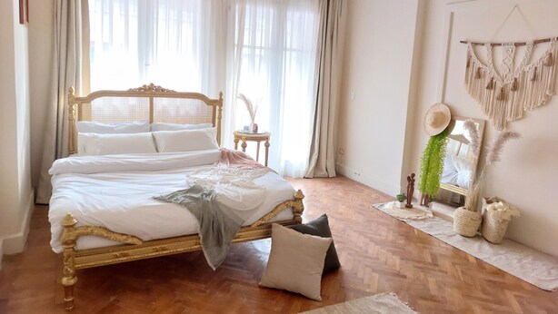 A bedroom with a wooden bed, white bedding, a small round table, and a macrame wall hanging. - El Otel Hotel (Cairo)