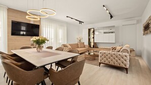 A modern living room with a dining area, featuring a large flat-screen TV, a sofa, a coffee table, and a fireplace. - Vacation home Tea by Interhome (Pula)