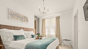 A modern bedroom with a large bed, a chandelier, a painting, and a window with curtains. - Vacation home Tea by Interhome (Pula)