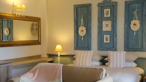 Une chambre d’hôtel avec deux lits, un canapé, un miroir et des cadres photos accrochés au mur.