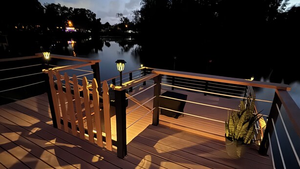 A wooden deck with railings overlooking a body of water, a bench, and a lamp post. - Pool and Fishing Lake Oasis (Port Richey)