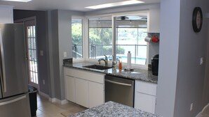 A kitchen with granite countertops, stainless steel appliances, and a window with a view of greenery. - Pool and Fishing Lake Oasis (Port Richey)