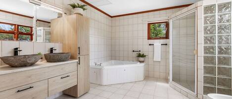 Un baño moderno con una bañera grande, una ducha a ras de suelo y un lavabo doble.