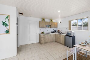 Efficient kitchen with gas stove, refrigerator, sink, and dining area.