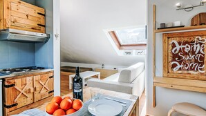 Et moderne køkken med træskabe, et spisebord dækket med en skål appelsiner, en vinflaske og et glas.