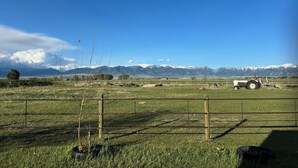 A rural landscape with a tractor in a fenced field, mountains in the background, and a clear blue sky.