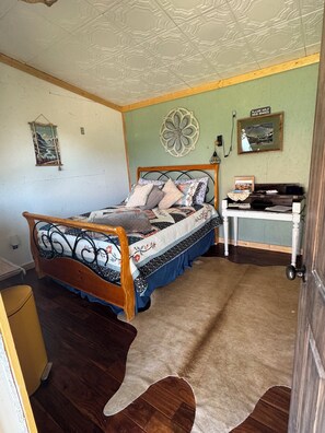 Ein Schlafzimmer mit einem hölzernen Bett, einem Schreibtisch mit Stuhl, einem Wanddekor und einem Poster an der Wand.