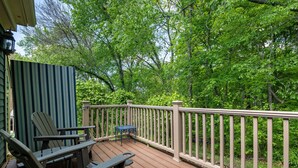 A wooden deck with a railing, chairs, and a table.
