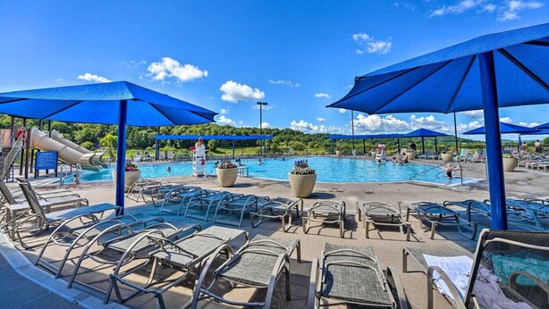 A pool area with lounge chairs, umbrellas, and a water slide.