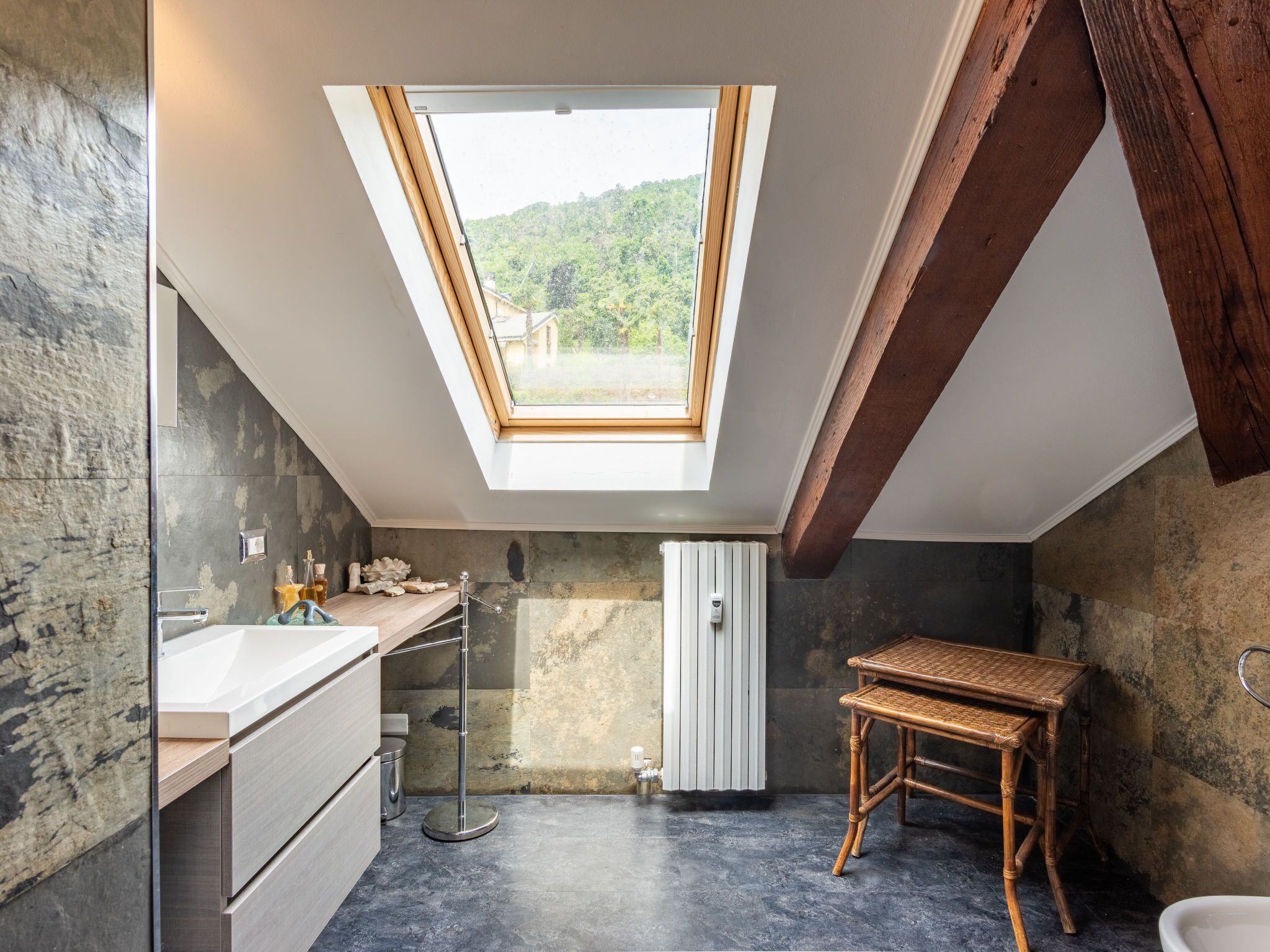 Une salle de bain moderne dotée d’un puits de lumière, d’un banc en bois et d’un grand miroir.