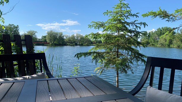 Una terraza de madera con vistas a un lago tranquilo y árboles circundantes.