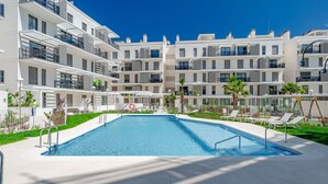 A modern apartment building with a swimming pool, multiple balconies, and a well-maintained garden area.