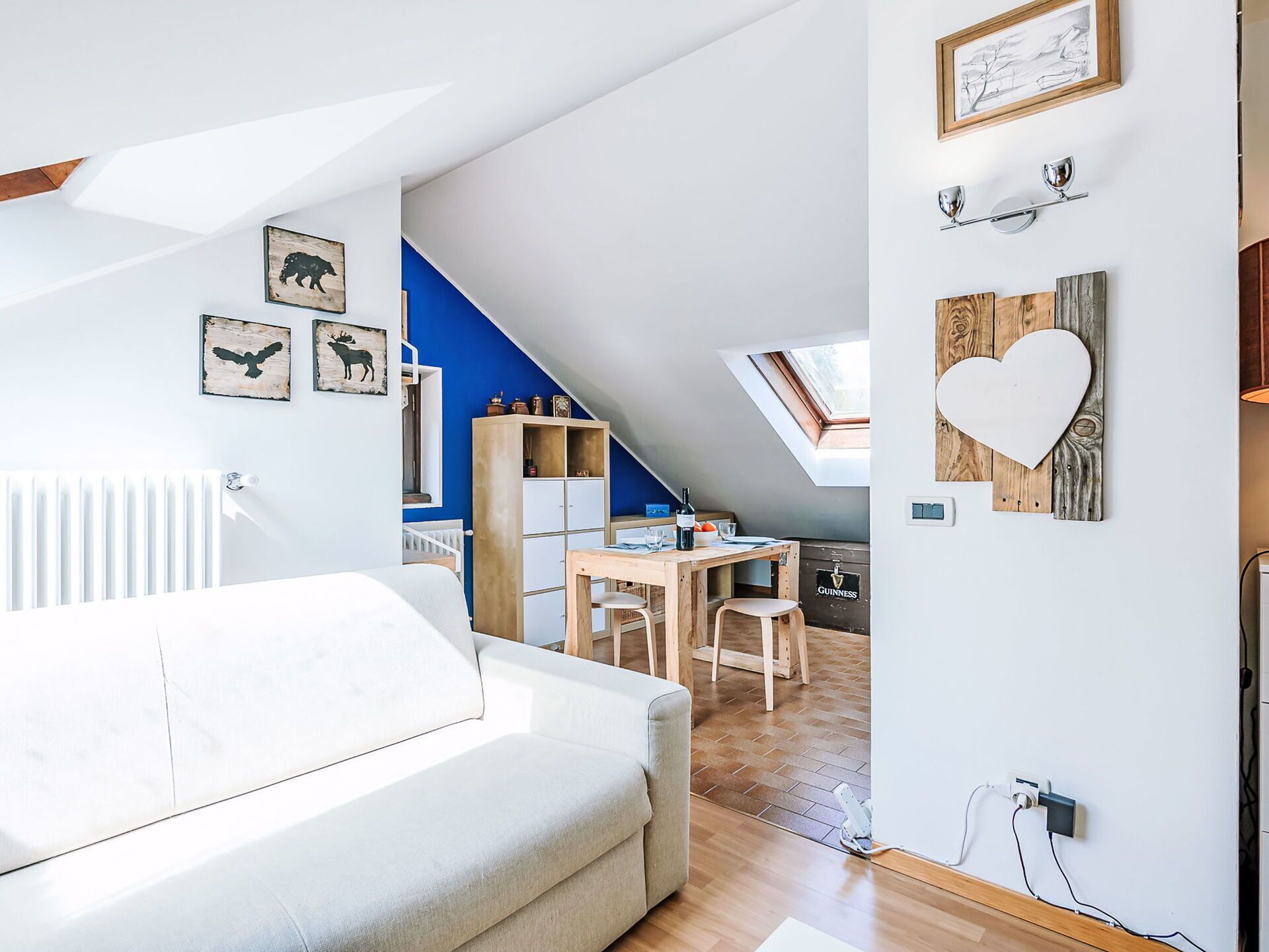 Un dormitorio estilo loft moderno con techo inclinado, tragaluz, un escritorio de madera y una zona de estar acogedora.