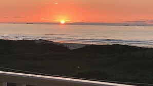 Un atardecer sobre un mar tranquilo con barcos a lo lejos.