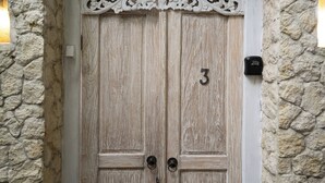 A wooden double door with the number 3, set in a stone wall with a decorative white frame above it. - Villa Chloe by Pertama Stay (Seminyak)