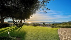 A well-maintained lawn with a paved walkway and a fence, overlooking a scenic landscape with hills and a clear sky.