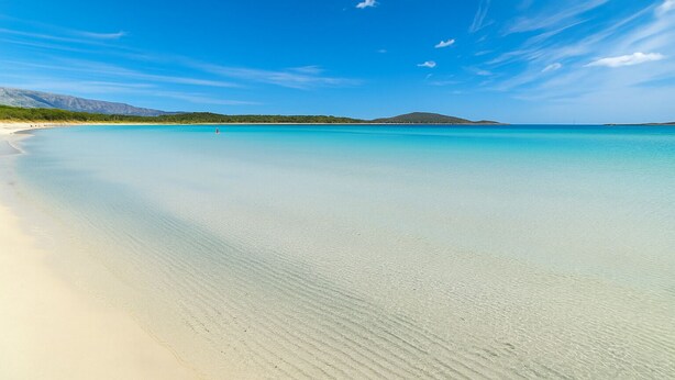 A beach with clear turquoise water and a sandy shore.