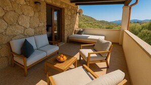 A balcony with stone walls, a sofa, a chair, and a table with oranges.