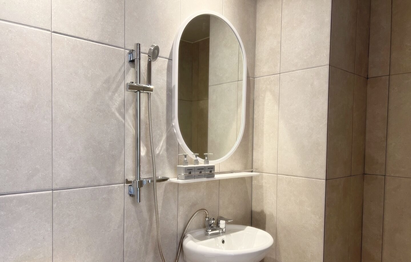 A modern bathroom with a shower, a sink, and a mirror.