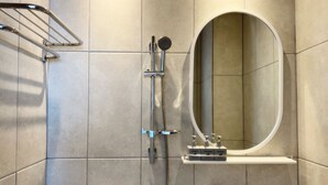 A modern bathroom with a shower, a toilet, and a sink with soap dispensers. - Gongzonestay (Jeju City)