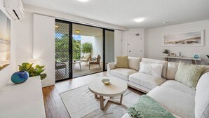 Una sala de estar moderna con un sofá, una mesa de centro y un ventanal corredero que da a un patio exterior.