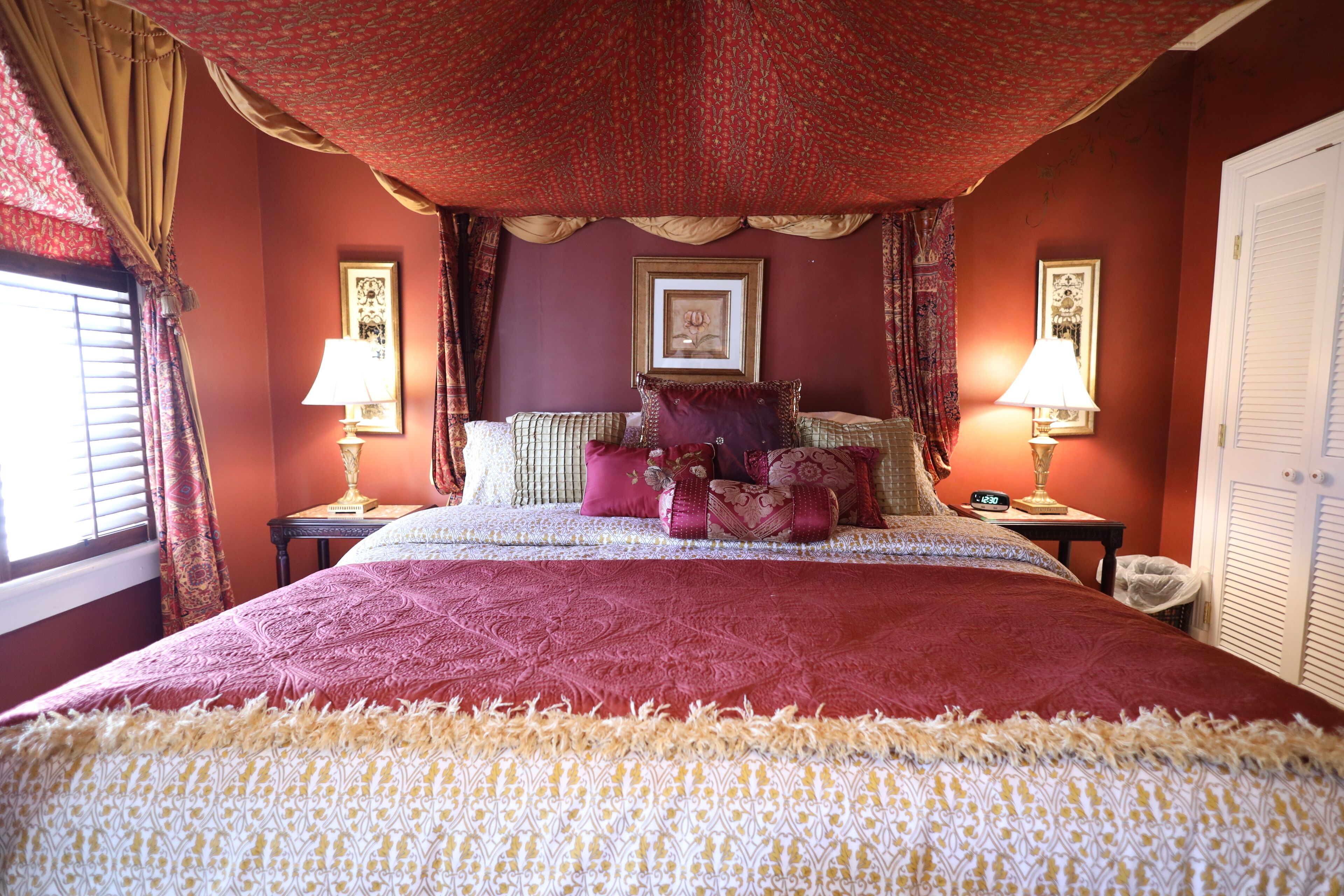 A bedroom with a large bed, two bedside tables with lamps, and a framed picture above the bed.