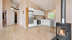 Een moderne keuken met houten wanden, een groot fornuis en een raam met uitzicht op groen.
