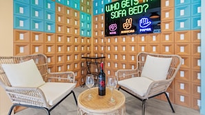 Una habitación con mobiliario de mimbre, un letrero de neón y una botella de vino.