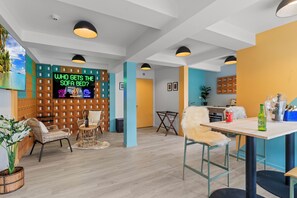 A modern hotel lobby with a neon sign, wicker furniture, and a wooden partition wall. - GY Boutique Hotel (Glenorchy)