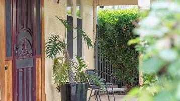 Un portico riparato con una pianta in vaso, una sedia e una porta con decorazioni.