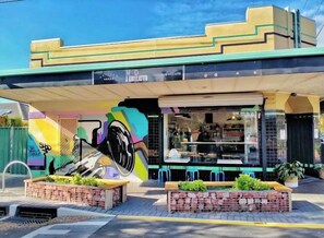 Un bâtiment orné d’une fresque murale, avec une devanture de magasin et des places assises à l’extérieur.