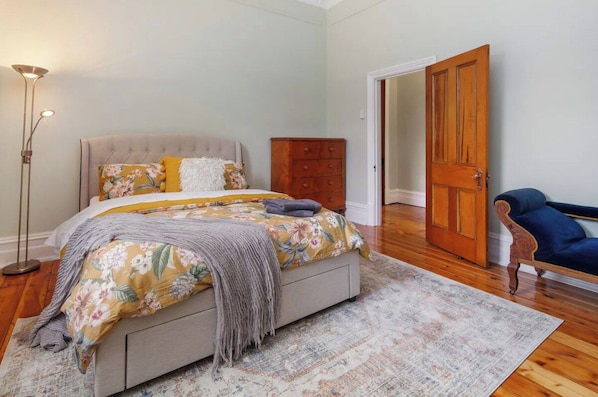 Quarto com cama, cômoda, cadeira e porta.