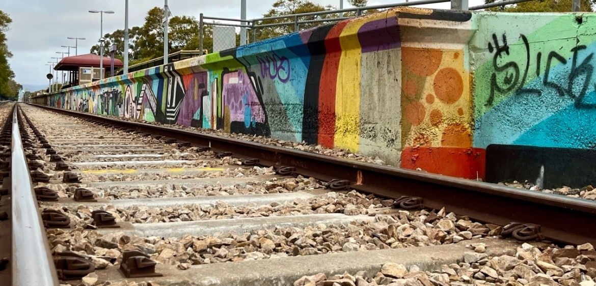 A railway track with colorful graffiti on the adjacent wall.