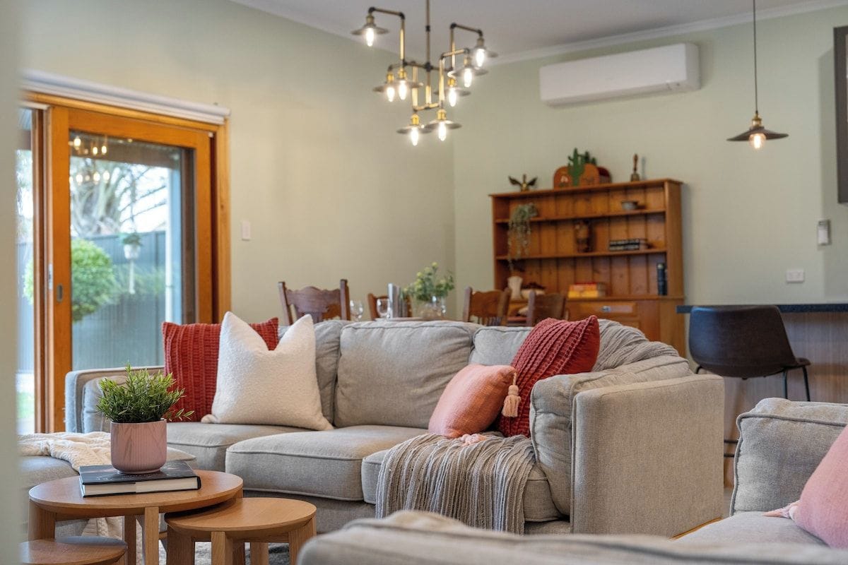 A modern living room with a sectional sofa, a small wooden table, and a bookshelf.