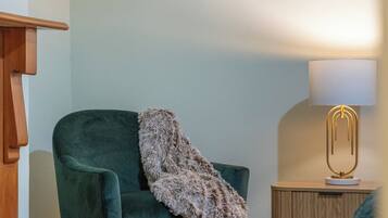A room with a green armchair, a wooden sideboard, and a lamp.