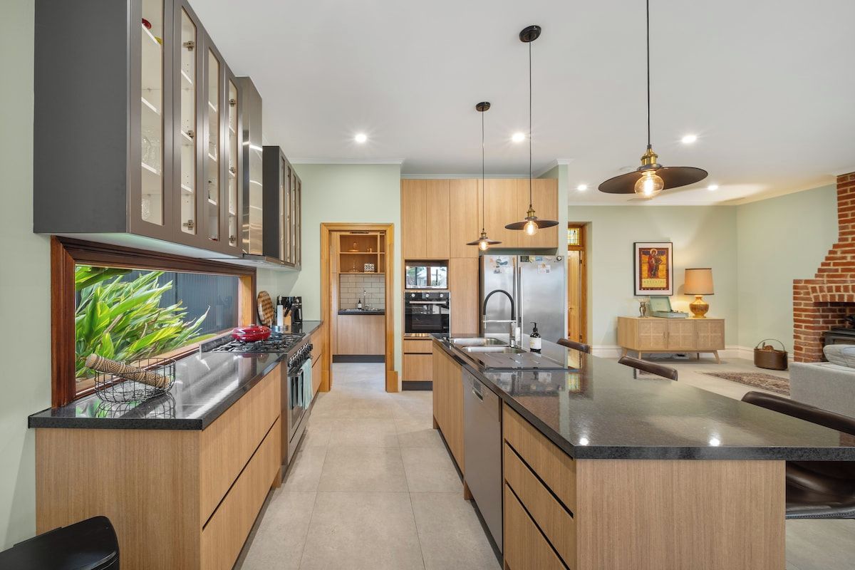 A modern kitchen with a central island, wooden cabinets, and a built-in oven.