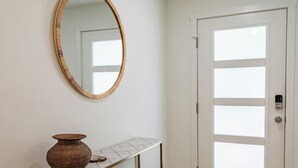 A hallway with a wooden console table, a woven basket, and a mirror on the wall.