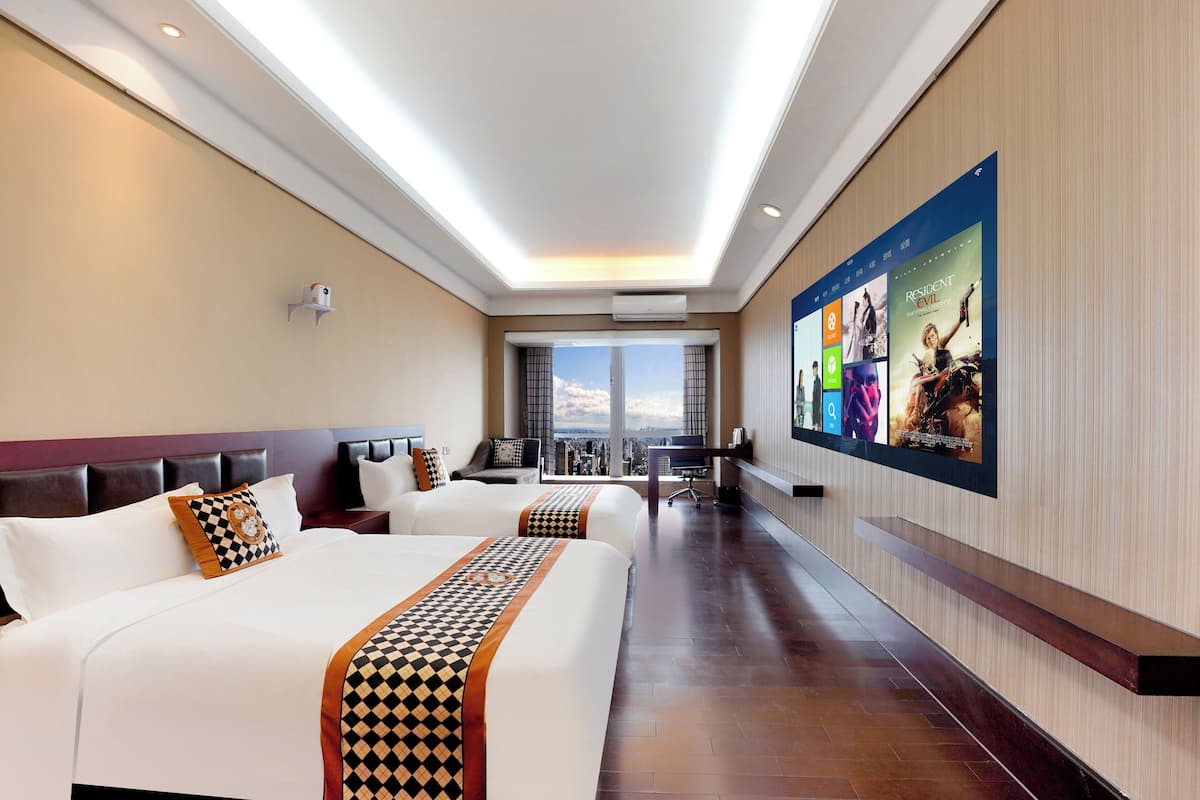 A hotel room with two beds, a desk, and a large window with a city view.
