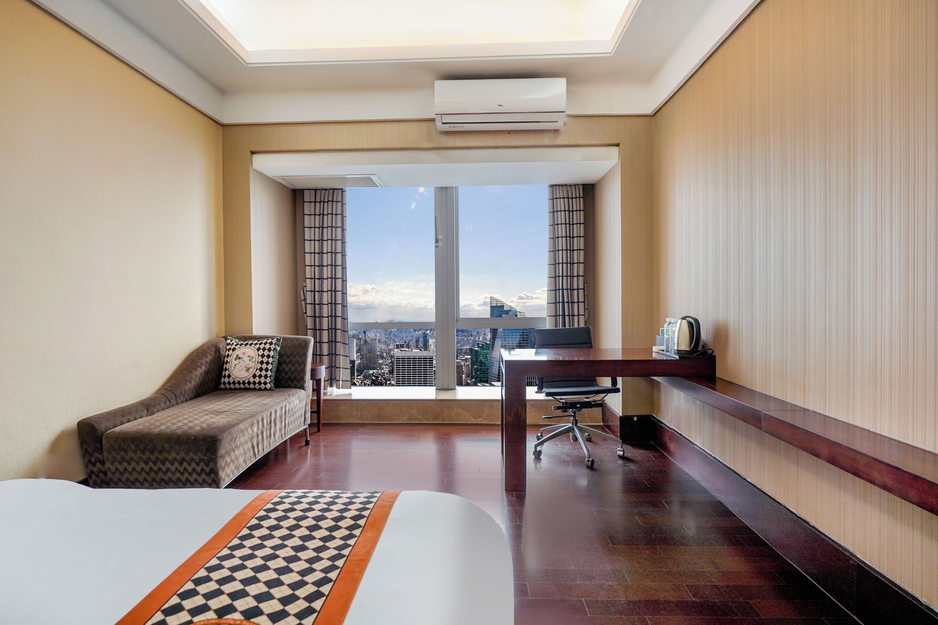 Una habitación de hotel con un ventanal grande, una cama, un escritorio y una silla.