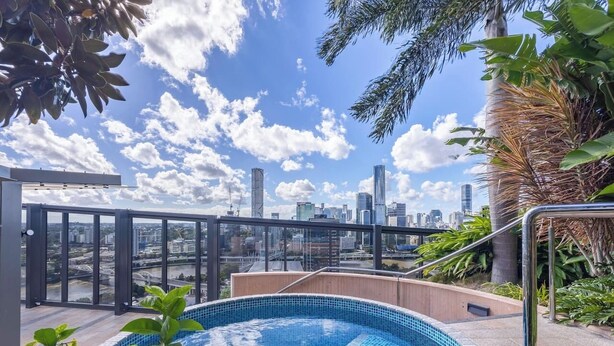 A rooftop pool with a city skyline view, surrounded by greenery. - Cityview 4 Beds/FR Carpark/pool at South Bank (South Brisbane)