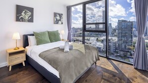 A bedroom with a large window, a bed, a nightstand, and a ceiling fan. - Cityview 4 Beds/FR Carpark/pool at South Bank (South Brisbane)